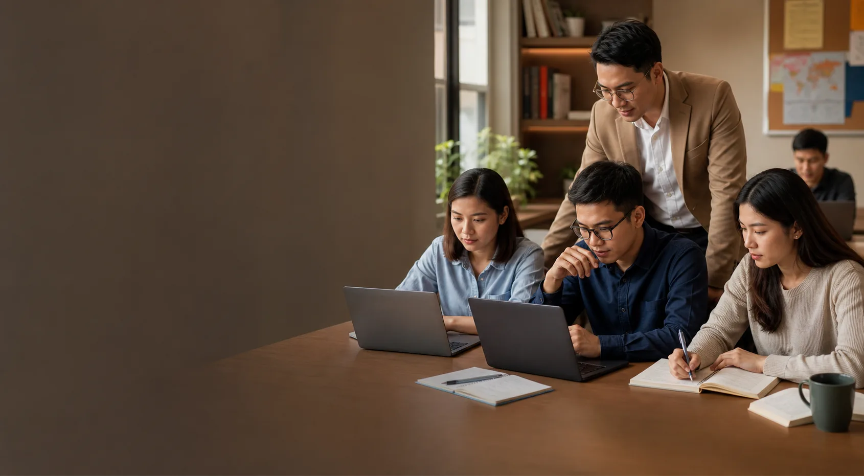 Lớp học hiện đại với giáo viên hướng dẫn nhóm học viên dùng laptop.